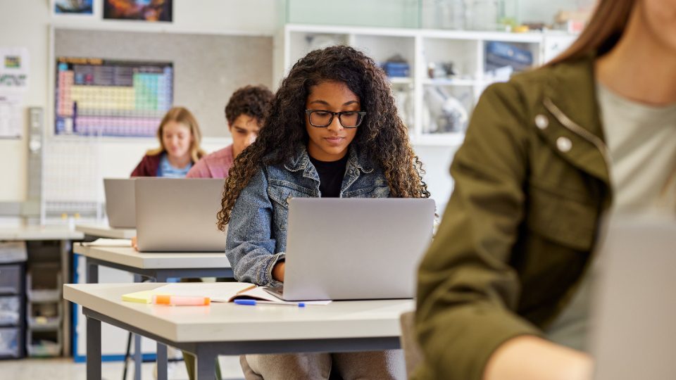 students in a classroom, each at their own desks with laptops