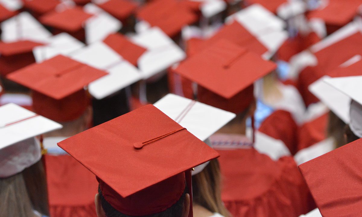 overhead shot of students wearing red and white graduation caps