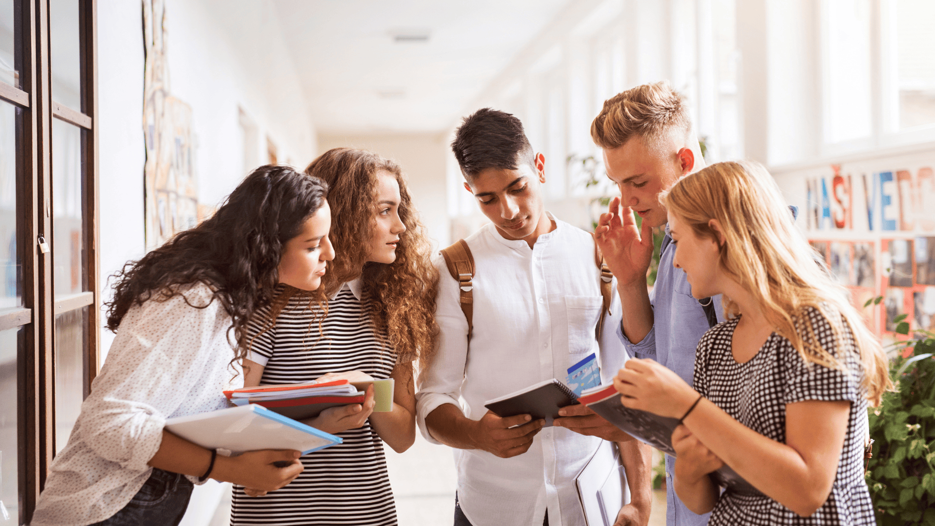 five high school students gathered together in a hallway