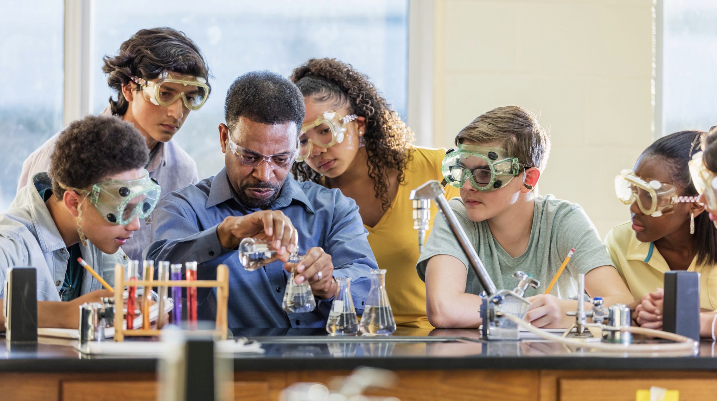 five students in a science lab with their teacher