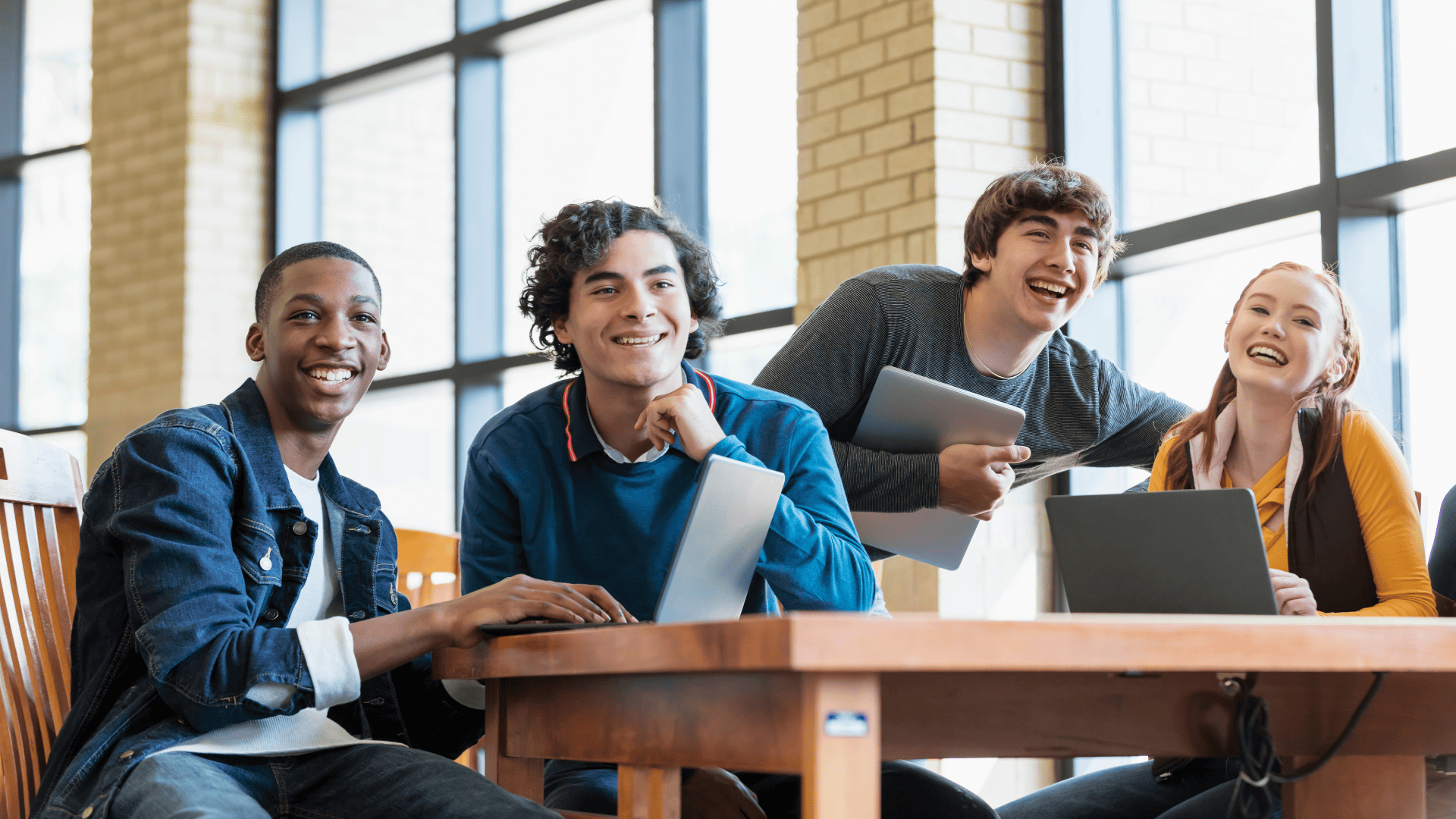 four smiling teenagers in a classroom