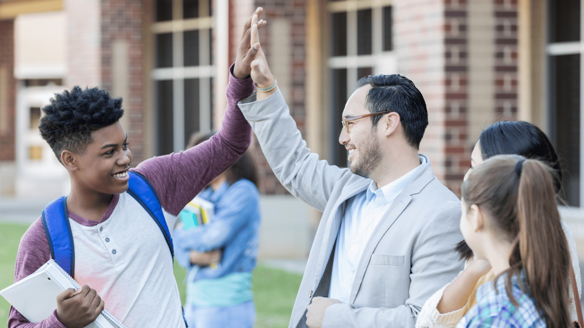 student and teach high fiving outside a school